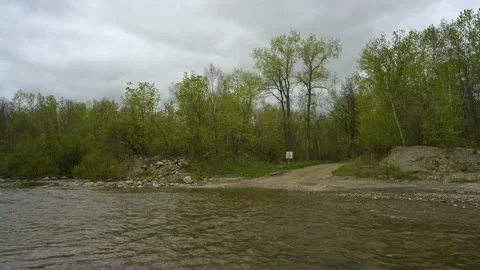 Small river with a ford crossing and a gravel road cutting through a forest. Stock Footage 155024324