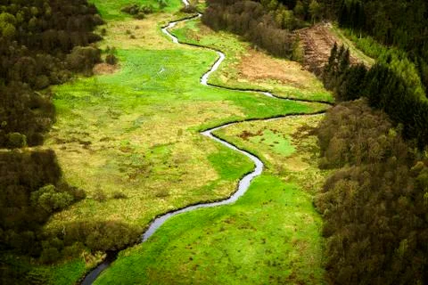 Small river going through a green area with fields Stock Photos