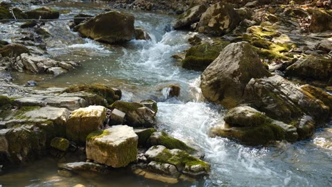 Small river in mountains at spring. Water flows down stones in strong stream Stock Footage 325963180