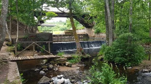 On small river there is an artificial waterfall under wooden bridge in the fo Foto stock