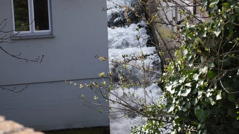 A small river turned into a waterfall. There is a white house on one side, and a 스톡 동영상 120026838