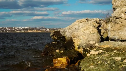 Small river waves splashing against colorful wet stone rock beach in time lapse Stock Footage 107332262