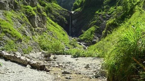 A small rivulet and grass moving in the wind in front of a slim waterfall Stock Footage 211500807