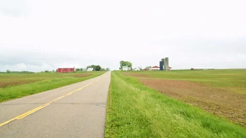 Small road by a farm with green fields on a rainy day. 4k60p Stock Footage 132357632