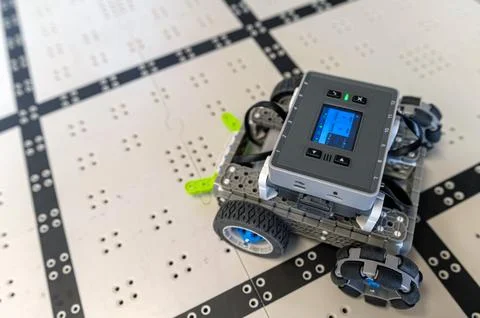 A small robot navigates a grid-like path, showing off its technology and sens Stock Photos