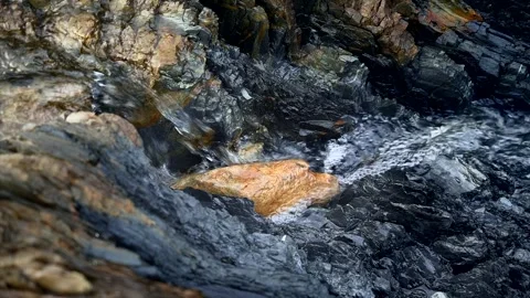 Small rock in a mountain river. Gray stone layers and small coastal waves. Stock Footage 256932875