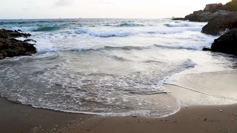 A small rocky beach with waves that roll into the sandy shore Video stock 153998493