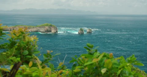 Small rocky islands emerge from deep blue sea under cloudy sky at Thousand Stock Footage 345689659