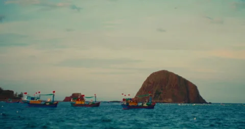 Small rocky islet stack and fishing boats floating on the open sea near the Stock Footage 342579598