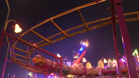 A small roller coaster at an amusement park, carnival or state fair at night. Stock Footage