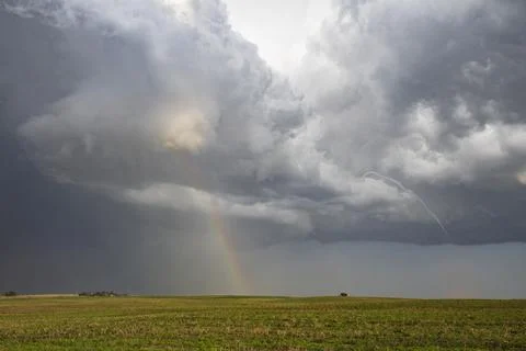 A Small Rope Tornado and a Double Rainbow in the sky above fields. Stock Photos