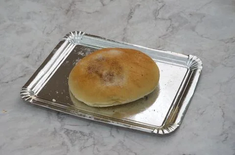 A small, round, brown bread sits on a silver tray Stock Photos