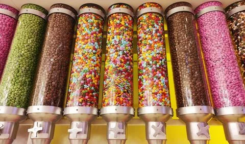 Small round candies covered with multicolored glaze in glass jars Stock Photos