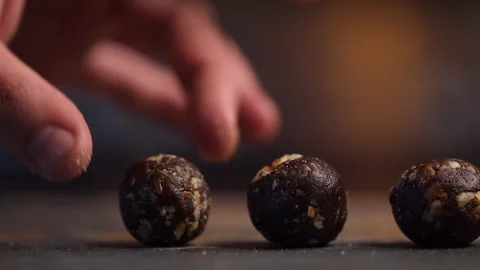Small round chocolate nut ball is set onto cookie sheet in bakery Stock Footage 301069709