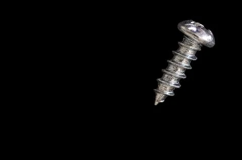 Small round head screw with a sharp point in extreme close up on a black ba.. Stock Photos