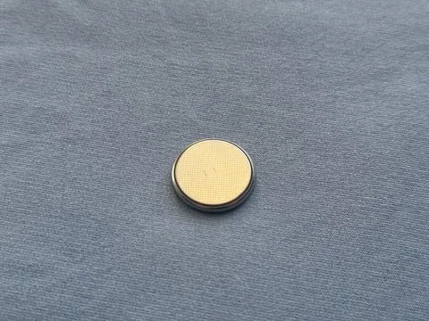 Small round metallic object on a gray fabric background Stock Photos