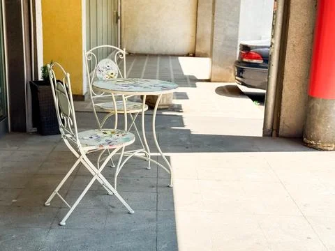 A small round table with two chairs in shade on the sidewalk. Illustration .. Stock Photos