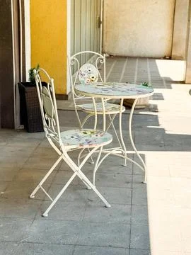A small round table with two chairs in shade on the sidewalk. Illustration of Stock Photos