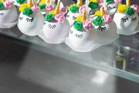 A small round unicorn cake is standing on a shelf in a bakery. The concept of Stock Photos