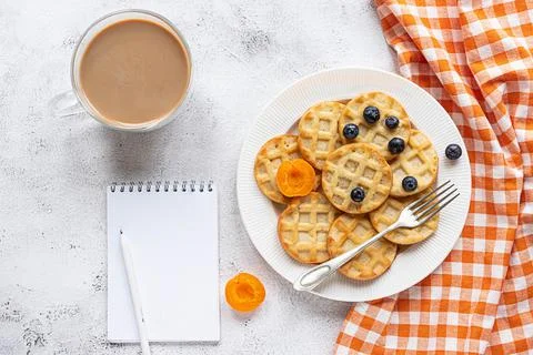 Small round waffles and a coffee on grey background, notebook, flat lay Stock Photos