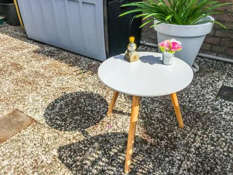 Small round white legged table with decorations on it in the backyard garden  Stock Photos