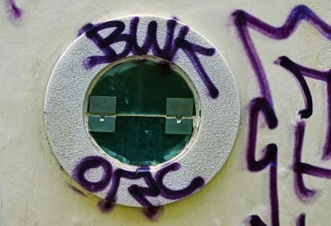 A small round window is painted with graffiti Stock Photos