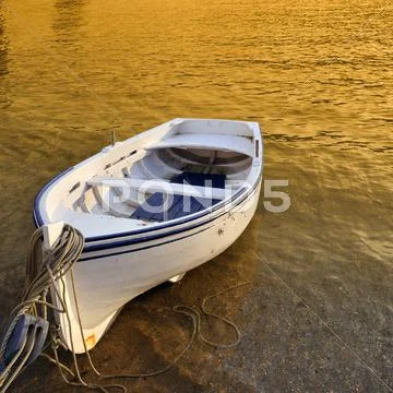 A Small Row Boat Beached On The Shore At Sunset - Cadaques, Spain