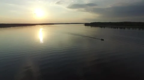 A small rubber boat fast floating on the river at sunset. Aerial view. Stock Footage 64816055
