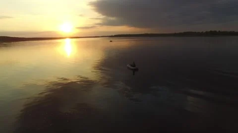 A small rubber boat floating on the river at sunset. Aerial view. Stock-Footage 64816304