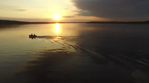 A small rubber boat moving quickly on the river at sunset. Aerial view. Stock-Footage 64816381