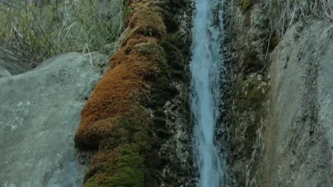 A small rushing stream of water pouring over a rock. Vídeos de archivo 163946198