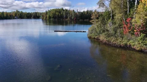 Small rustic dock, highlighting clear water and autumn foliage Stock Footage 346557471