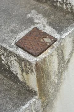 Small rusty metal plate embedded in concrete stairs Stock Photos