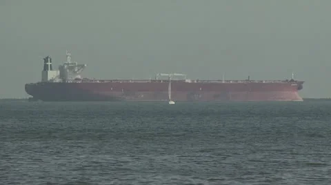 Small Sail Boat Passing A Huge Ship On the Ocean Video stock 19130882