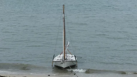 Small sailboat anchored on a beach, being rocked by the waves Video stock 286259088