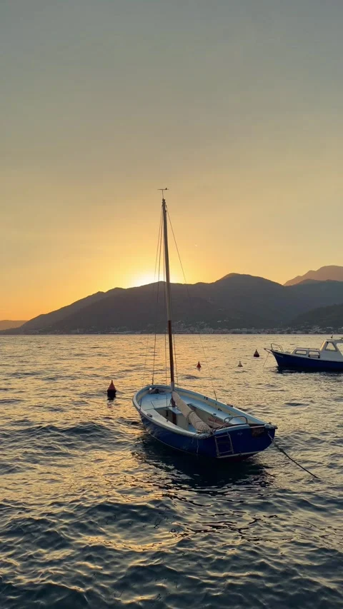 Small sailboat gently rocking on waves in the Adriatic Sea at sunset, with Stock Footage 346693152