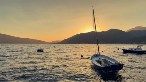 Small sailboat gently rocking on waves in the Adriatic Sea at sunset, with Stock Footage 346693596