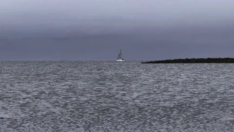 Small sailboat sailing out to the ocean under threatening storm clouds 動画素材 293740159