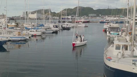 Small sailing boat brings down sail whilst docking in Bodo Marina Stock Footage 284490169