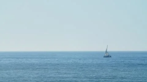 A small sailing boat is sailing in the open ocean on a bright sunny summer Stock Footage 329694648