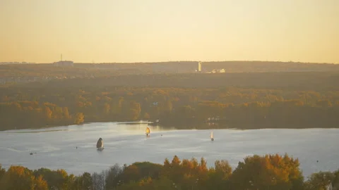 Small sailing yachts in the bay at sunset. Surrounded by an orange forest Stock Footage 163374696