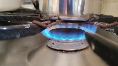 A small saucepan on a stove being lit and a gas flame emerging from it Vídeo Stock 334334138