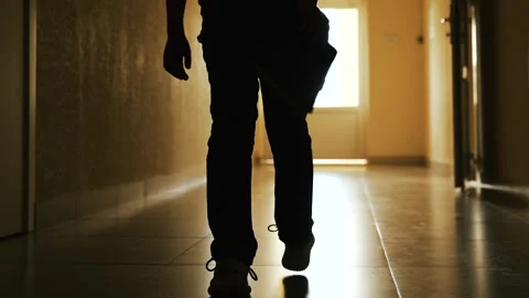 Small school boy walks with book down dark hallway toward light. Lonely Stock Footage 318658058