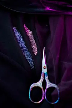 Small scissors lie on a dark cloth next to the beads Stock Photos