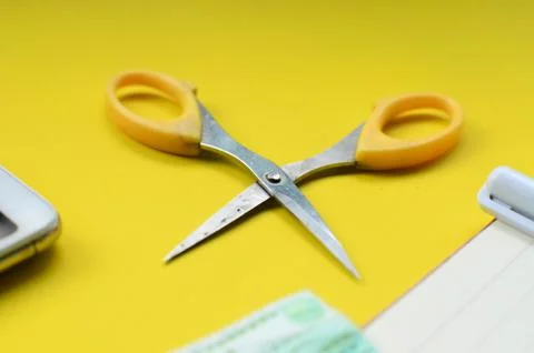 Small scissors on a yellow background Foto stock