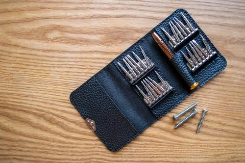 Small screwdriver with interchangeable bits lies on a wooden table, top view. Foto stock