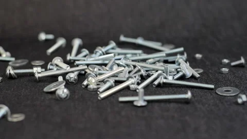 Small screws and nuts for repair are poured onto the table Stock Footage 159866762