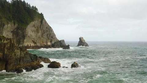 Small sea stack protruding from turbulent Pacific Ocean off rocky Oregon Stock Footage 270112174