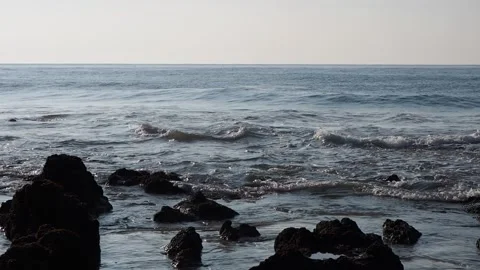 Small sea waves breaking on the small rocks on the beach. Vídeos de archivo 260264033