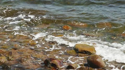 Small sea waves hitting brown stones, in slow motion Vídeos de archivo 259826104
